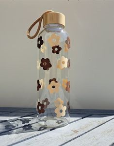 a clear glass bottle with brown and white flowers on it