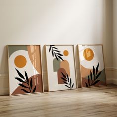 three framed art pieces sitting on top of a wooden floor