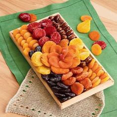 a wooden box filled with dried fruit on top of a green table cloth next to a napkin