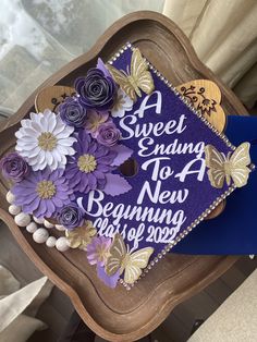 a purple graduation cap with flowers and butterflies on the side that says, a sweet ending to a new beginning is 2009