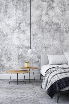 a bedroom with a bed, nightstand and table in front of a wall that is painted gray