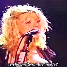 a woman singing into a microphone with the words, is she pretty on the inside?