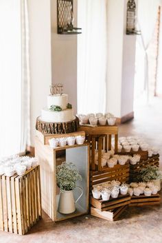 a table topped with lots of cupcakes next to a cake on top of a wooden box