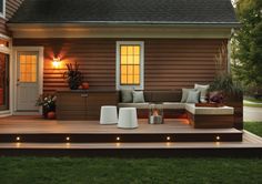 an outdoor living area with lights on the steps and couches in front of it