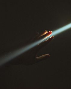 a person's hand holding a flashlight in the dark with light coming from it