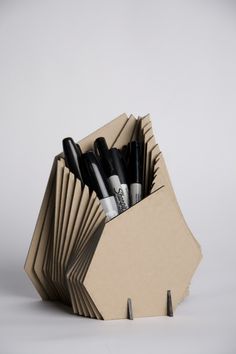 an open cardboard box with pens and pencils in it