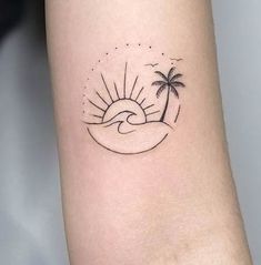 a small tattoo on the arm of a woman with a palm tree and sun in the background