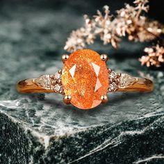 an orange diamond ring sitting on top of a rock