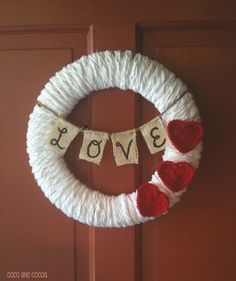 a yarn wreath with the word love hanging from it's side on a door