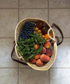 a basket filled with fruit sitting on top of a tiled floor