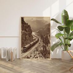 a black and white photo of a train going down the tracks with mountains in the background