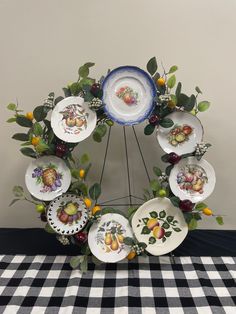 a table topped with lots of plates covered in fruit and leaves on top of a black and white checkered table cloth