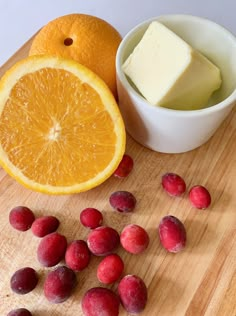 an orange and some fruit on a cutting board next to a bowl of cream cheese