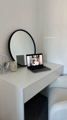 a laptop computer sitting on top of a white desk next to a mirror and lamp