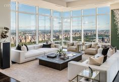 a living room filled with lots of furniture and large windows overlooking the cityscape