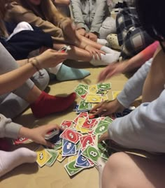 a group of people sitting around each other playing with stickers on the floor in front of them