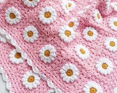 a crocheted blanket with white and yellow flowers