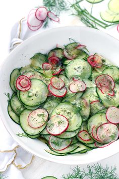 a white bowl filled with cucumbers and radishes on top of a table