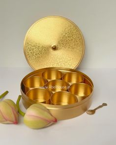 an open metal container filled with lots of gold colored items next to tulips