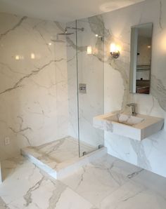 a bathroom with marble walls and flooring next to a walk - in shower stall