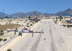 an airplane is flying low over a dirt road in front of some mountains and desert