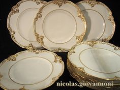 five white and gold plates stacked on top of each other in front of a black background