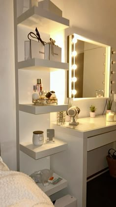 a white vanity with lights on it next to a mirror and shelf filled with cosmetics