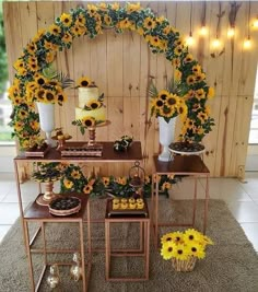 sunflowers and other flowers are arranged on tables in front of a wooden wall