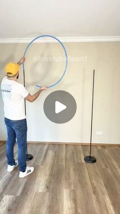 a man holding a blue hula hoop on top of a hard wood floor