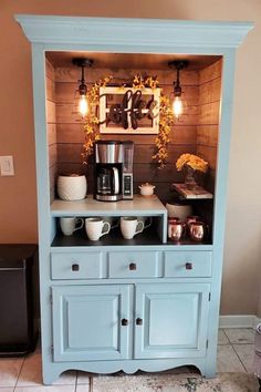 a blue hutch with coffee maker and cups on it's side, sitting in front of a brown wall