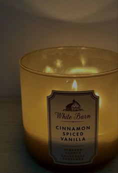 a candle that is sitting in front of a glass bowl with cinnamon spiced vanilla on it