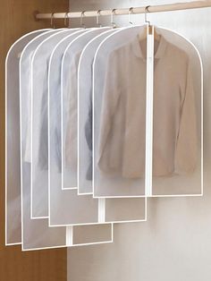 five shirts hanging on a rack in front of a door with clothes hanging from it