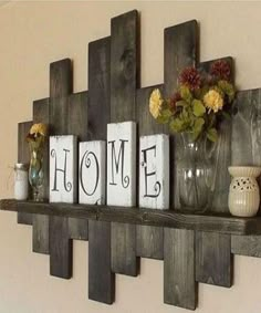 some wooden blocks are sitting on a shelf with vases and flowers in them that spell home