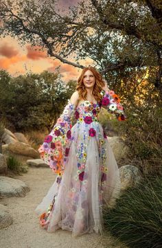 a woman in a dress standing on a dirt road