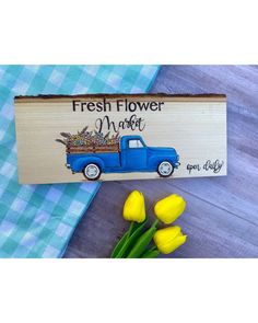 a wooden sign that says fresh flower market next to yellow tulips