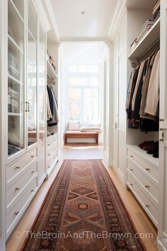 an organized walk in closet with white cabinets and drawers, carpeted flooring and built - in shelving