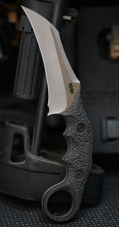 a close up of a knife on the ground near a piece of metal and black material