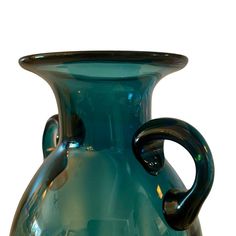 a blue glass vase sitting on top of a white table next to a black handle