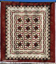 a red and white quilt hanging on the side of a building with a blue sky in the background