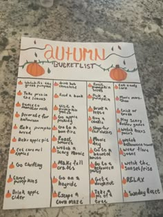 an autumn bucket list with pumpkins and leaves on the top, sitting on a granite countertop