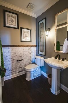 a white toilet sitting next to a sink in a bathroom under framed pictures on the wall