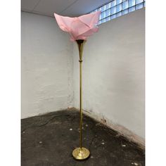 a floor lamp with a pink flower on it in an empty room next to a window