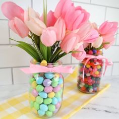 two vases filled with candy and flowers on a table