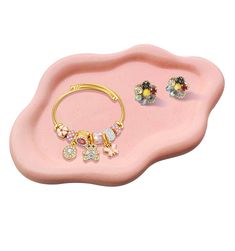 a pink tray with three different jewelry pieces on it