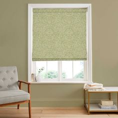 a living room with a chair, window and green roller shades on the windowsill