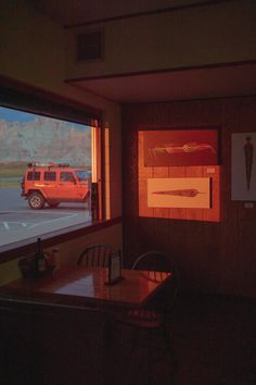 a red truck is seen through the window of a restaurant with mountains in the background