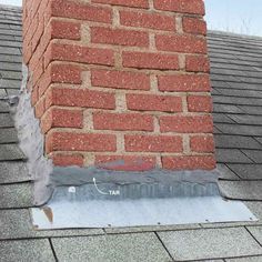 a brick chimney on top of a roof that has been gutted with asphalt and cement