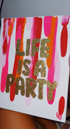 a woman holding up a sign that says life is a party with gold glitter paint on it