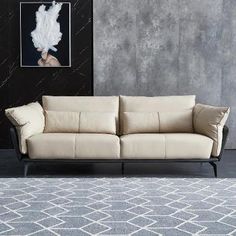 a white couch sitting in front of a painting on a wall next to a rug