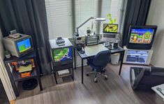 a living room filled with furniture and two tvs on top of desks next to each other